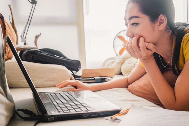 Woman sitting at desk stares at her laptop.