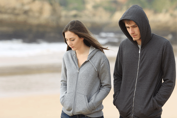 couple walking along beach looking moody